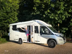 Ein Wohnmobil steht auf einem Waldparkplatz parkiert.