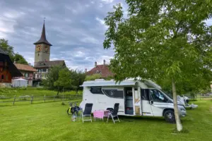 Wohnmobilplatz auf einer Wiese mit Kirche im Hintergrund.