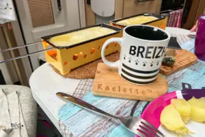 Auf dem gedeckten Tisch köchelt der Raclette Käse vor sich hin.