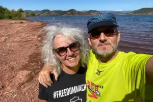 Eine Frau und ein Mann stehen am See und machen ein Selfie von sich.