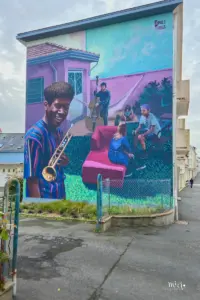Eine Fassadenmalerei zeigt ein Bild einer musizierenden Familie.