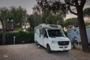 Wohnmobil parkiert unter Bäumen auf dem Stellplatz für die Nacht.
