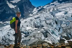 Eine Frau in Wanderausrüstung steht am Fusse des Fee Gletscher in den Bergen bei Saas Fee.