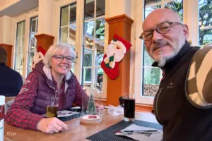 Eine Frau und ein Mann sitzen im Restaurant, das weihnachtlich dekoriert ist und warten auf das Essen.