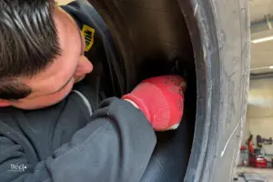 Mechaniker repariert einen demontierten Fahrzeugreifen von innen mit einem Reifenreparatur-Kit.