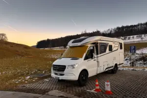 Wohnmobil steht auf einem Parkplatz am Rande von Feldern.