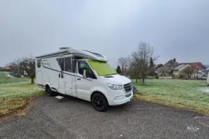 Wohnmobil steht auf einem Parkplatz am Rande von Feldern.