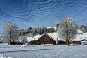 Ein typisches Appenzeller Bauernhaus steht in der verschneiten Winterlandschaft.
