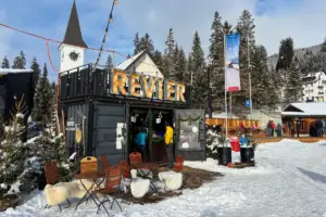 Auf dem Dorfplatz steht ein Fracht-Container der zu einer Bar umfunktioniert wurde mit einer kleinen Gartenwirtschaft davor.