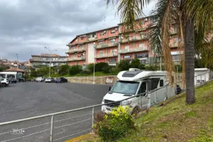 Wohnmobil steht auf dem Parkplatz vor einer Wohnüberbauung.