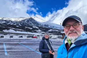 Zwei Menschen posieren für ein Erinnerungsfoto mit dem Ätna im Hintergrund.