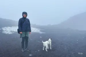 Eine Frau mit Hund in der nebelverhangenen Landschaft des Vulkans.