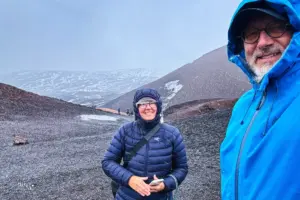 Zwei Menschen posieren vor dem Loch eines Nebenkraters des Ätna.