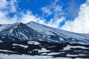 Der Ätna zeigt sich aus dem Wolken verhangenen Himmel.