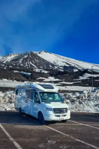 Wohnmobil steht unterhalb des Ätnas vor den Schneefeldern.