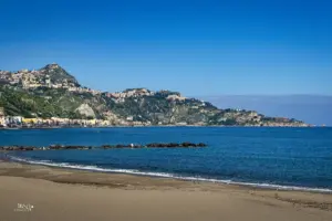 Blick vom Strand über das Meer zu den Hügeln von Taormina.