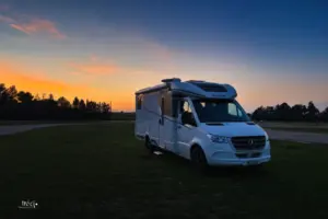 Hinter dem parkierten Wohnmobil ist der Sonnenuntergang zu sehen.