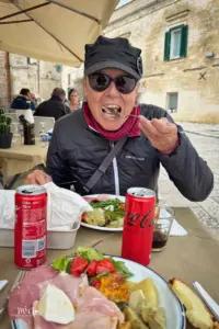 Eine Frau sitzt in der Gartenwirtschaft einer Osteria und ist am Essen.