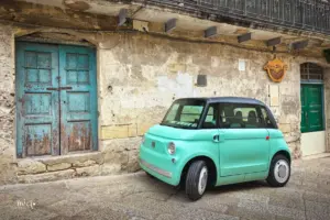 Ein Microcar steht in einer kleinen Seitengasse in der Altstadt Materas vor einem Haus parkiert. Seine türkis Farbe ergibt einen reizvollen Kontrast zu dem alten Gebäude.