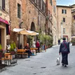 Eine Frau läuft mit ihrem Hund durch die kleinen Gassen der Altstadt von Montepulciano.