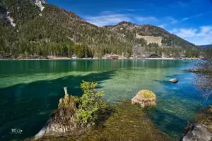 In tiefem grün präsentiert sich der Toblacher See, ein Bergsee in den Dolomiten der eingerahmt wird von den stolzen Bergen die um diese Jahreszeit noch einen weisse Schneekrone tragen.