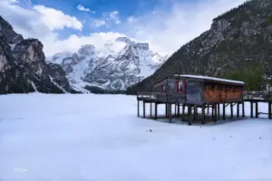 Aus dem gefrorenen See ragt das Bootshaus fast surrealistisch auf den Pfählen raus.