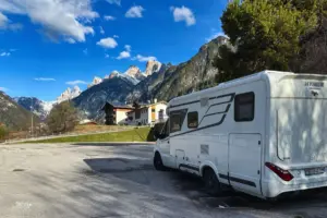 Ein Wohnmobil steht an der Entleerungsstelle und lässt das Abwasser vom Tank in den Abwasserschacht. Im Hintergrund sieht man die Bergspitzen der Dolomiten.