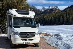 Wohnmobil steht parkiert in der winterlichen Landschaft.
