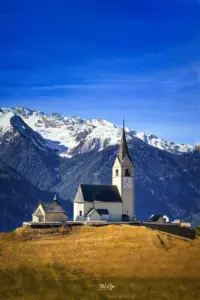 Die Kirche im kleinen Bündner Dorf Schmitten steht erhaben und dominant im Dorf auf einer Anhöhe.