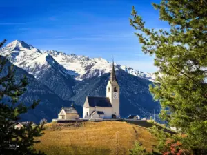 Die Kirche im kleinen Bündner Dorf Schmitten steht erhaben und dominant im Dorf auf einer Anhöhe.
