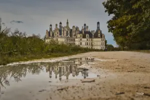 Auf dem Spazierweg zum Schloss Chambord spiegelt sich das Schloss in einer Pfütze.