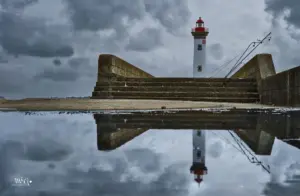 Bei tristem und regnerischem Wetter spiegelt sich der Leuchtturm von Saint-Nazaire in einer Wasserpfütze.