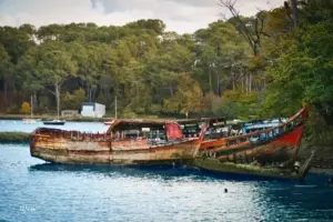 Mehrere alte Fischerboote zerfallen langsam und modern im Wasser vor sich hin.