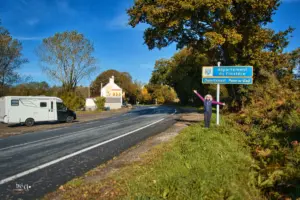 Auf der kleinen Landstrasse steht ein Wohnmobil am Strassenrand mit der Tafel die den Departementswechsel anzeigt gegenüber.
