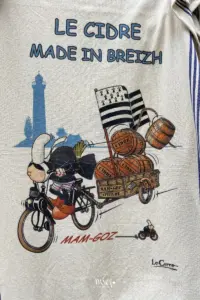Ein typisches Sujet der Bretagne, die alte Bretonin ohne Gesicht fährt mit dem Solex und Anhänger die Cidre Fässer aus.