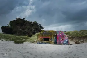 Der triste Bunker am Strand wird durch die künstlerische Gestaltung zum farbigen Kunstwerk und gleichzeitig durch die Kunstwerke zum Mahnmal.