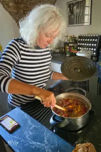 Eine Frau steht am Kochherd und kocht die Früchte ein für Konfitüre.