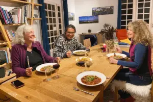 Am schönen Holztisch sitzen alle bereit und warten darauf mit dem essen anzufangen.