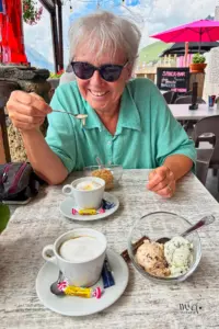 Lachende Frau geniesst den Kaffee mit dazugehörigem Dessert.