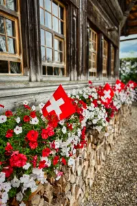 Schweizer Fähnchen und Geranien zieren die Hausfront des typischen Emmentaler Bauernhaus.