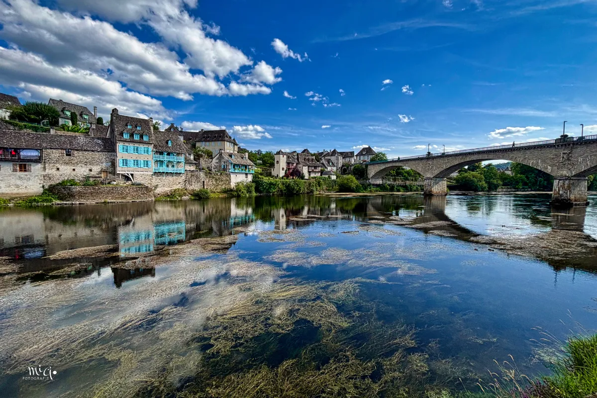Spiegelglatt ist das Wasser der Dordogne wo sich die Häuser und der Himmel spiegeln im Wasser.
